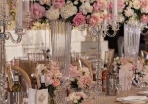 A table set with silverware and plates, flowers in vases.